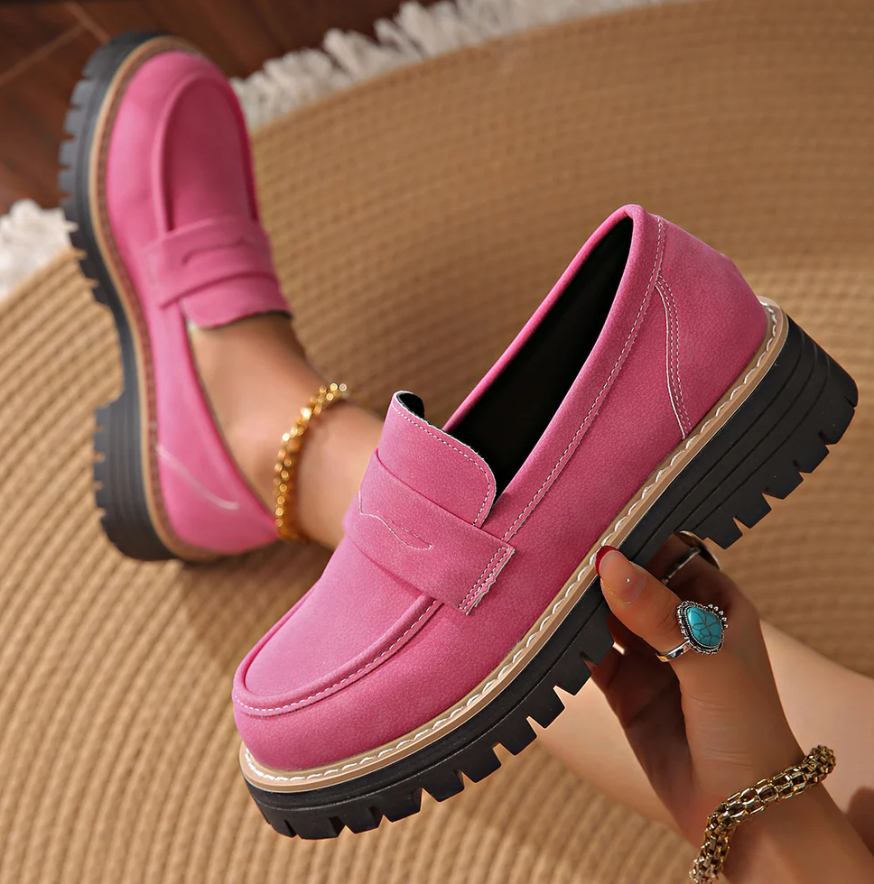 Pinke Wildleder-Loafer mit Plateausohle, ein Schuh in der Hand gehalten, auf einem Flechtteppich. 18