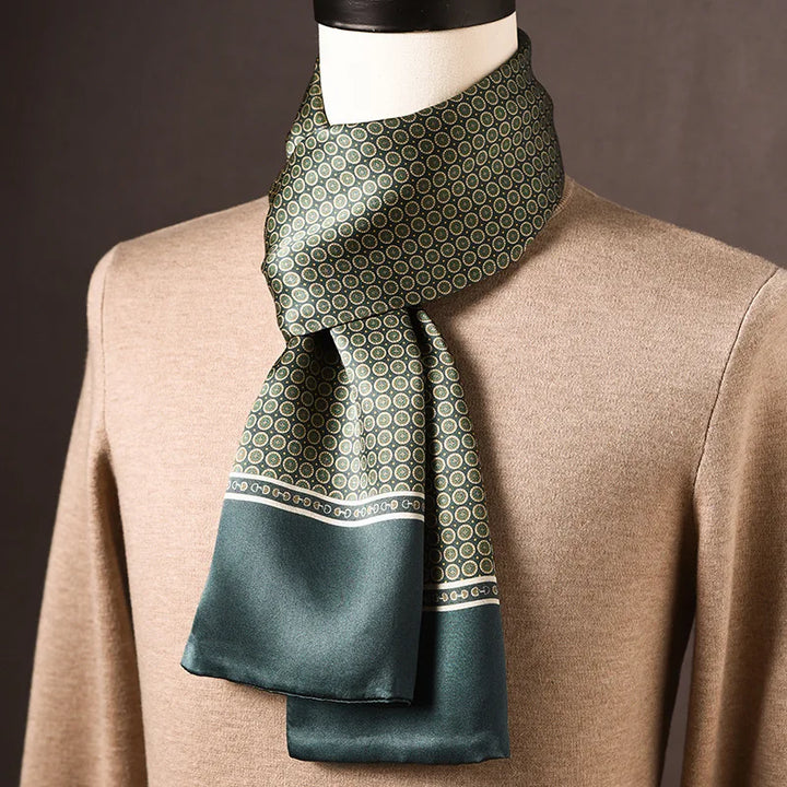 Grüner Seidenschal mit kleinen kreisförmigen Motiven und breitem grünem Rand, an einer Büste über beigem Pullover. 8