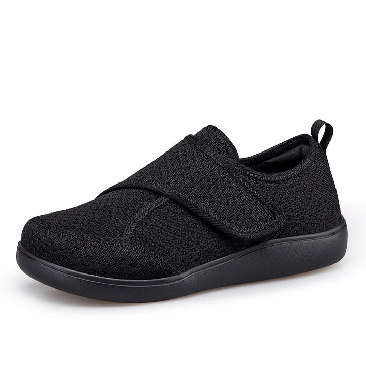 Schwarzer Klettverschluss-Schuh aus Netzgewebe mit schwarzer Sohle, Seitenansicht schräg von vorn 1