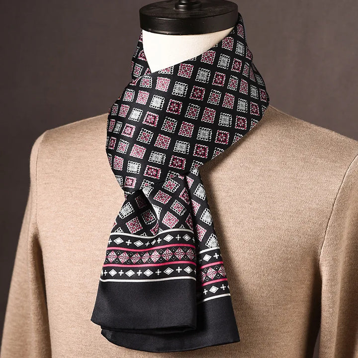 Schwarzer Seidenschal mit rosa-weißen Rautenmotiven und gemusterter Bordüre mit rosa Streifen, über beigem Pullover an einer Büste. 15