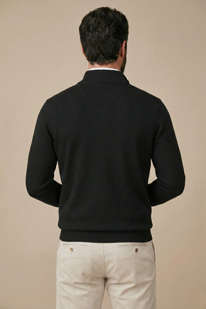 Rückansicht des schwarzen Pullovers am Model mit Stehkragen und Rippbund, beige Hose 2
