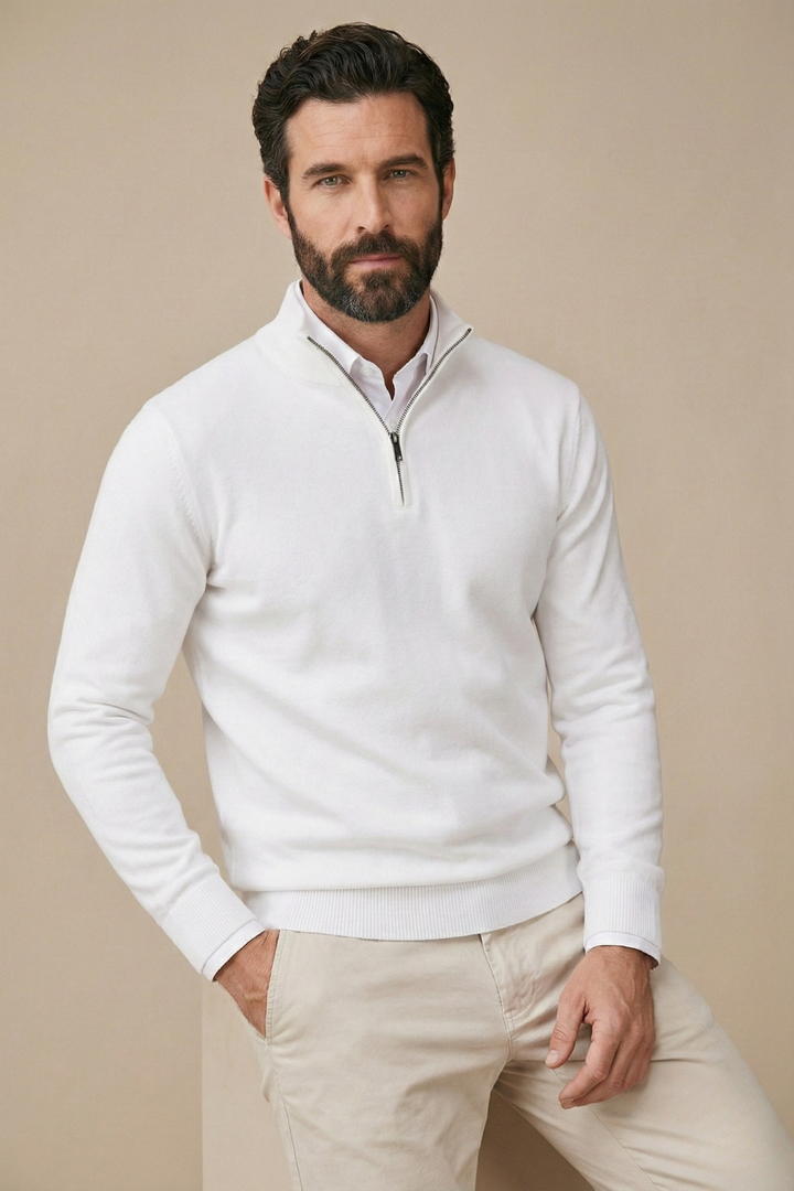 Model in weißem Pullover mit halbem Reißverschluss, lässig an eine Kante gelehnt 3