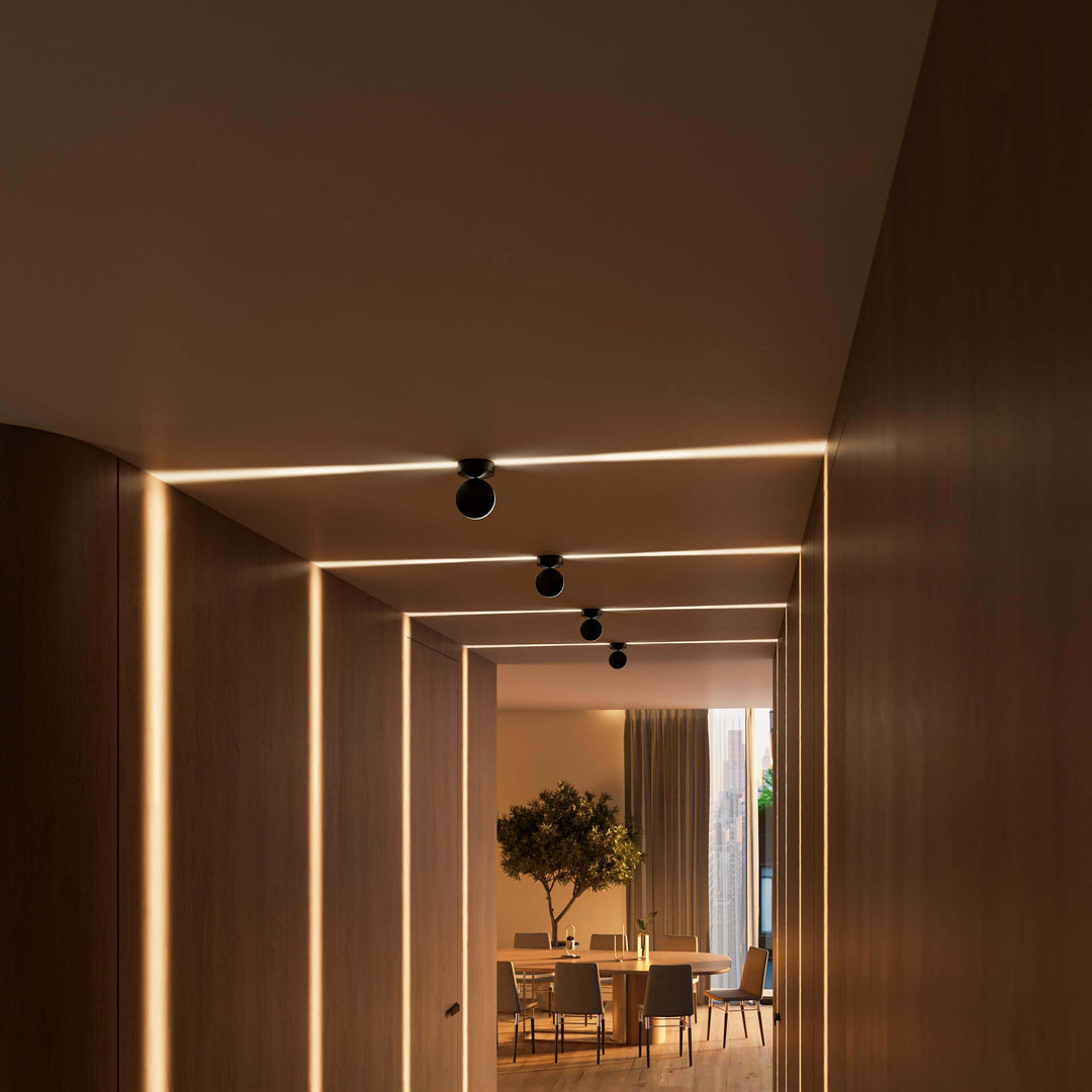 Schwarze Deckenleuchten in einem Holzflur mit waagerechten Lichtlinien an der Decke und senkrechten Streifen an den Wänden. 14
