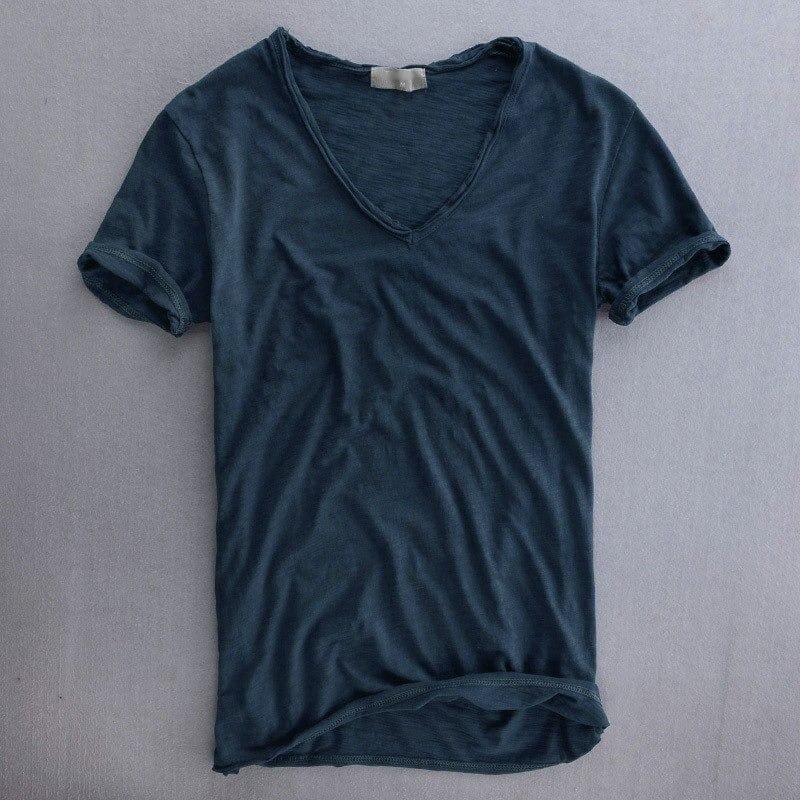 Dunkelblaues V-Ausschnitt-Shirt mit kurzen Ärmeln, flach auf grauem Untergrund liegend, feine Strukturoptik des Stoffes erkennbar. 5