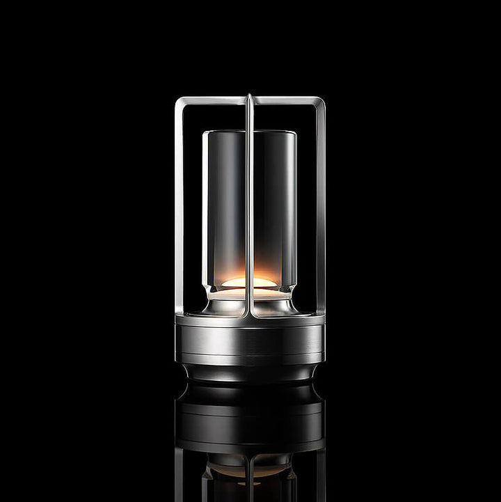 Leuchtende Tischlampe in Silber mit Metallrahmen und Glaszylinder, freigestellt vor schwarzem Hintergrund. 10
