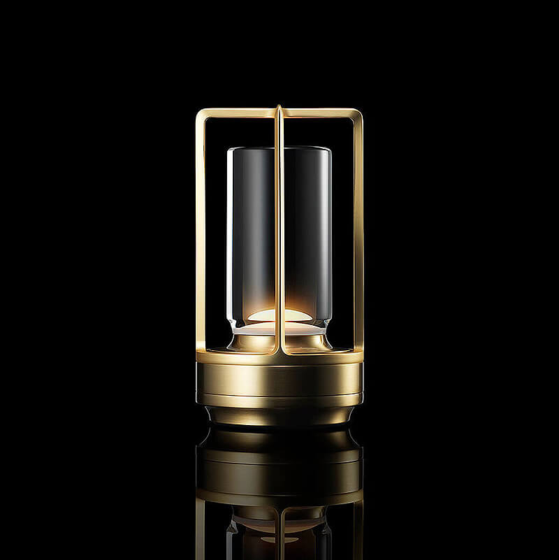 Leuchtende Tischlampe in Messing-Optik mit goldenem Metallrahmen und Glaszylinder vor schwarzem Hintergrund. 1