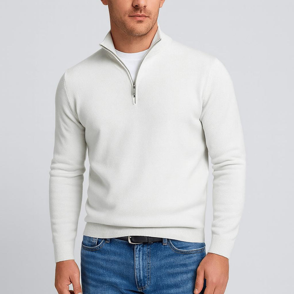 Mann trägt den Pullover in Weiß mit Stehkragen und silbernem Reißverschluss, kombiniert mit Jeans und schwarzem Gürtel. 2