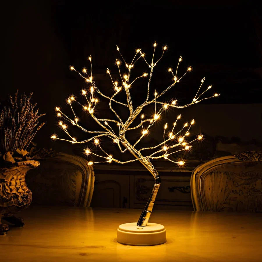 Beleuchteter Lichterbaum mit weißem Sockel auf einem Tisch, links eine Vase mit Trockenblumen 2