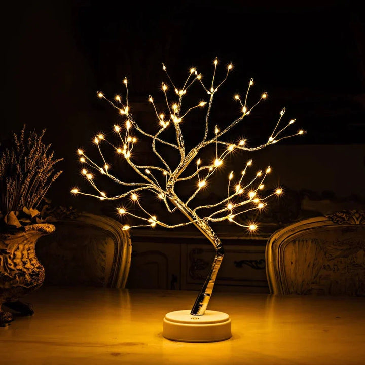 Beleuchteter Lichterbaum mit weißem Sockel auf einem Tisch, links eine Vase mit Trockenblumen 2