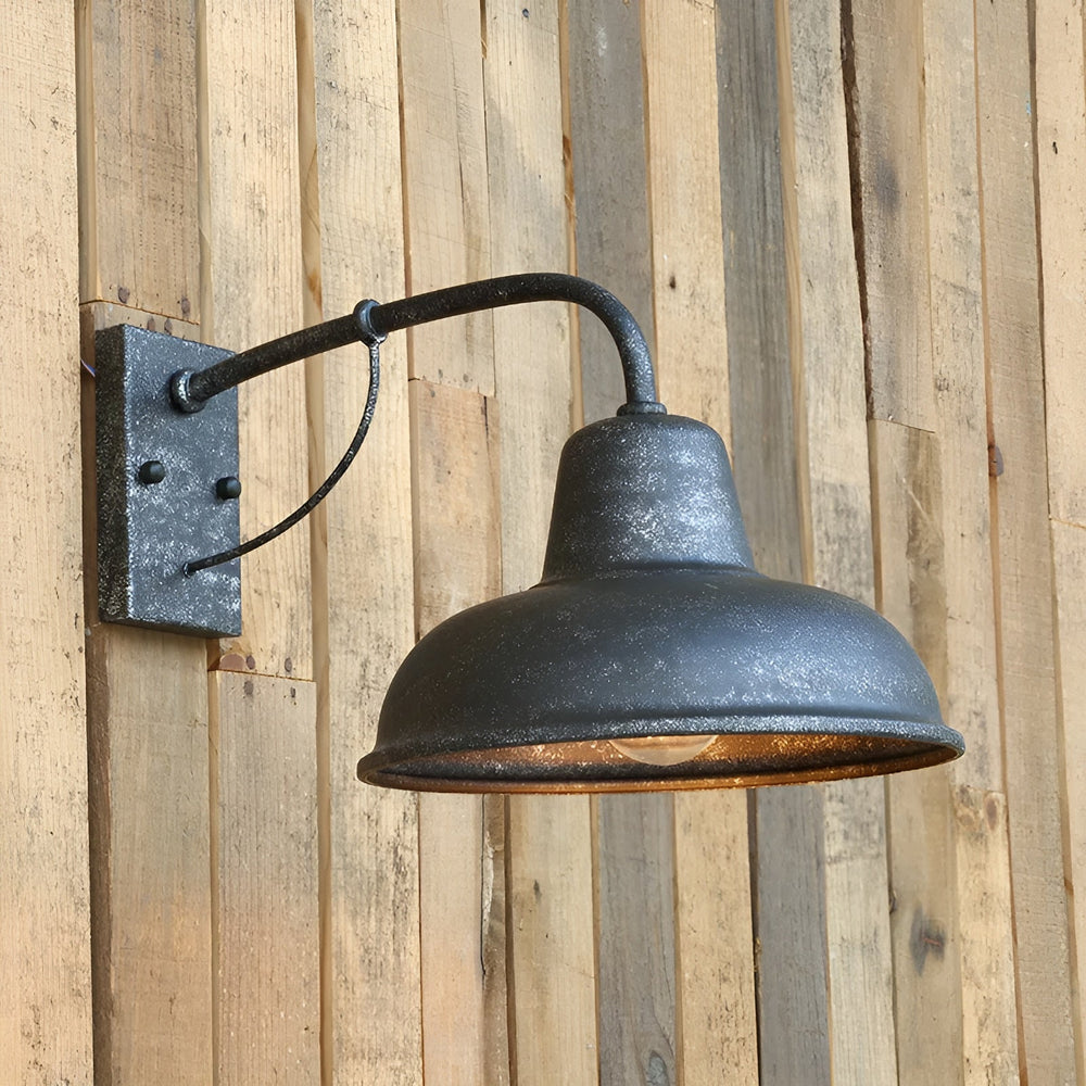 Wandlampe in rustikaler, verwitterter Optik mit körniger Oberfläche, an einer Wand aus hellen Holzbrettern montiert, die Glühbirne leuchtet warm. 2