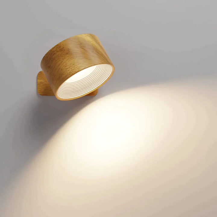 Wandlampe in Holzoptik mit weißem, gerilltem Innenring, leuchtet warm und beleuchtet die Wand darunter. 3