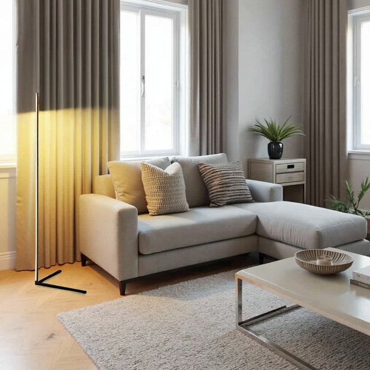 Stehlampe taucht einen beigen Vorhang in warmes Licht, daneben ein helles Ecksofa mit Kissen und Couchtisch 10