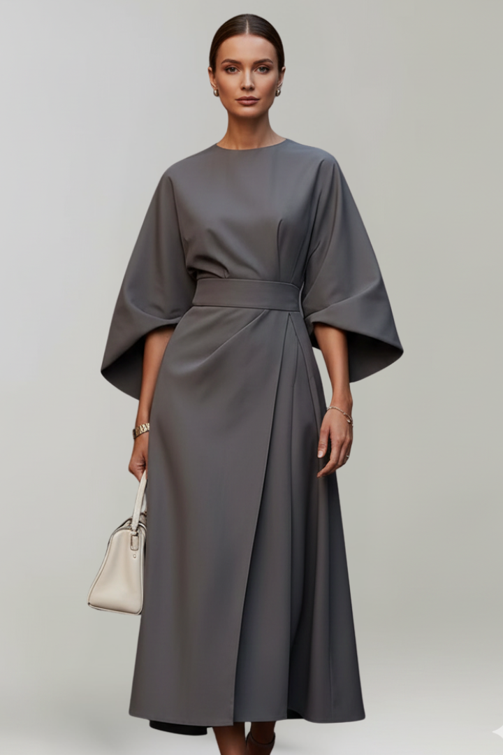 Model in grauem Kleid frontal, mit heller Handtasche, weiten Ärmeln und ausgestelltem Wickelrock 10