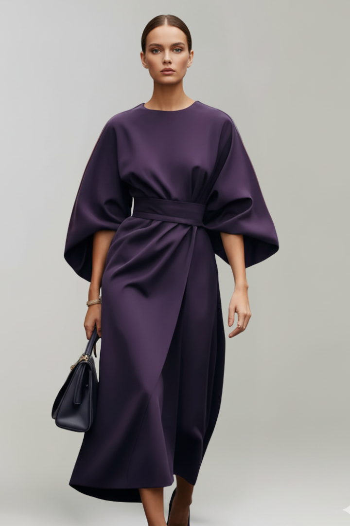 Model in dunkelviolettem Kleid frontal, mit dunkler Handtasche und weit fallenden Ärmeln 9