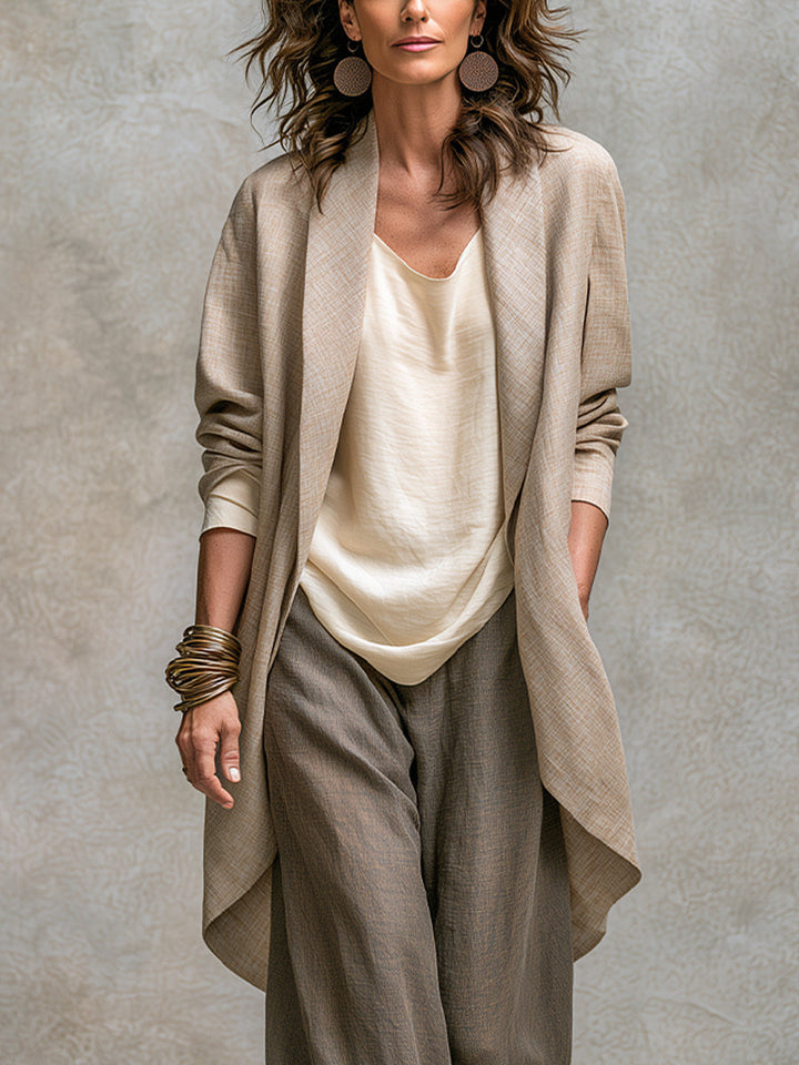 Nahaufnahme des langen offenen Jacketts in Beige mit Schalkragen und abgerundetem Saum, getragen über Oberteil und Hose. 3