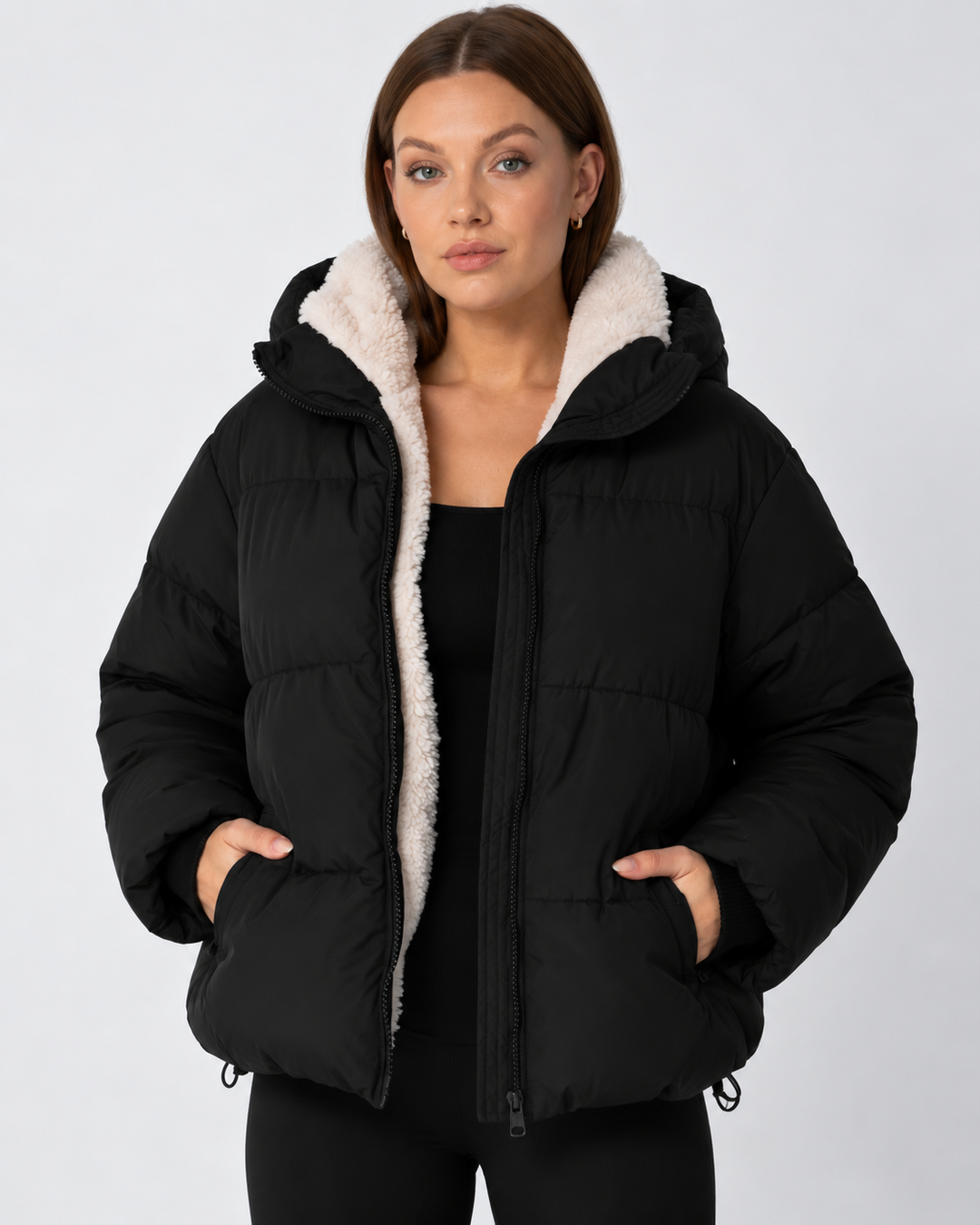Frontansicht der schwarzen Steppjacke mit hellem Teddyfutter, Hände in den Taschen, Kordelzug am Saum 11