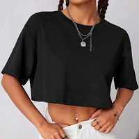 Frau trägt schwarzes Crop-Top, weiße Hose, Silberschmuck, modisches Outfit, Freizeitkleidung.