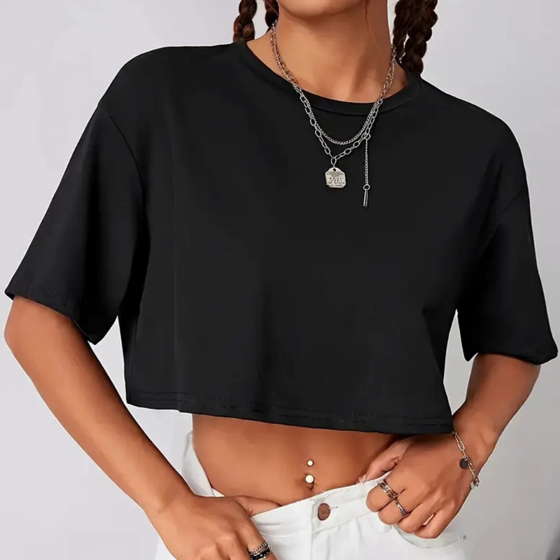 Frau trägt schwarzes Crop-Top, weiße Hose, Silberschmuck, modisches Outfit, Freizeitkleidung.