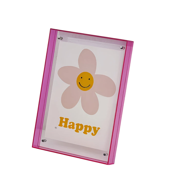 Freigestellter Rahmen mit pinkem Acrylrand und Silberschrauben, darin ein Druck mit lächelnder Blume auf weißem Grund. 1