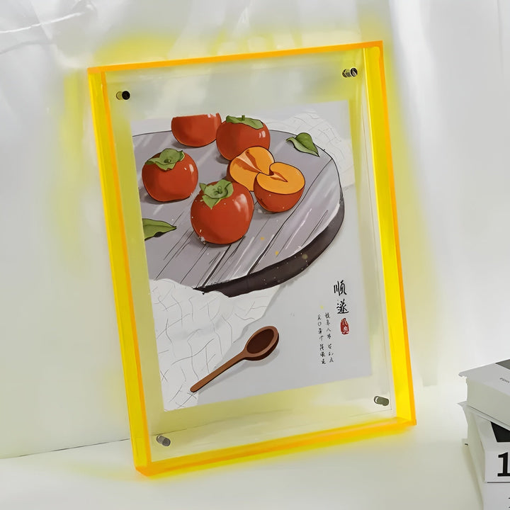 Gelber Acrylrahmen mit Illustration von Kakis auf einem Teller und einem Holzlöffel, an einer Wand aufgestellt. 12