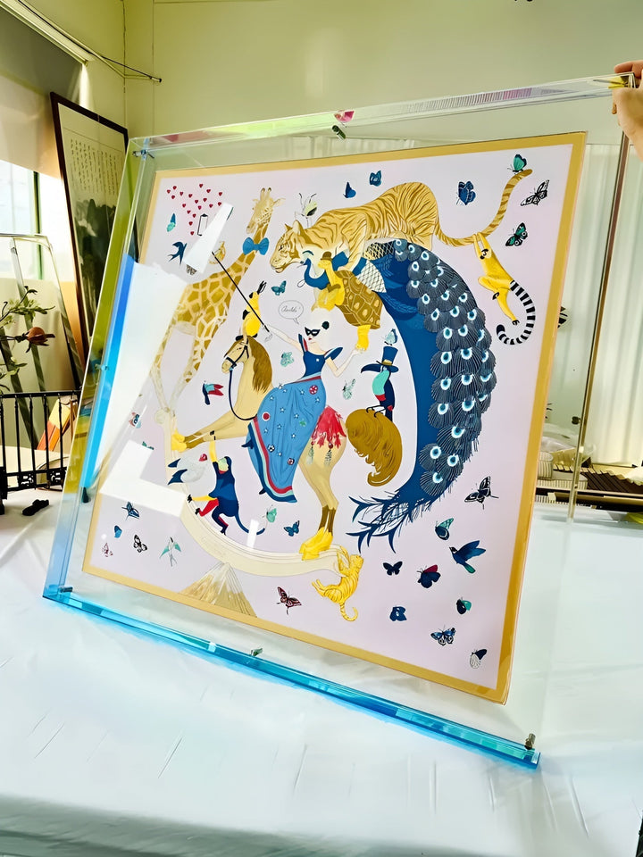 Großer Acrylrahmen mit hellblauem Rand, von einer Hand gehalten, darin ein Tuch mit Tieren, Pfau, Tiger und Schmetterlingen. 17