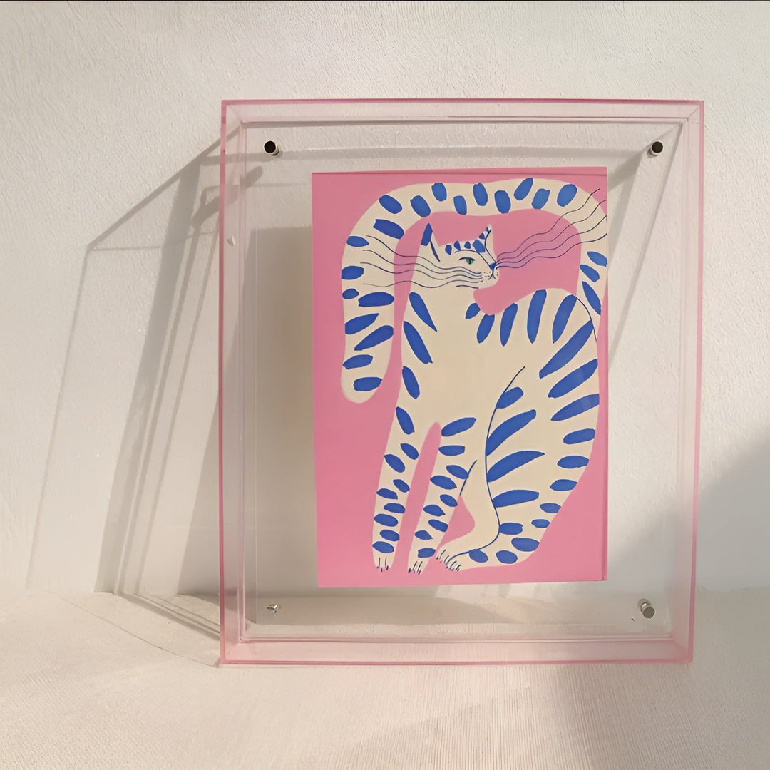 Transparenter Rahmen mit zartem rosa Rand, darin ein rosa Druck mit gestreifter Katze in Blau und Weiß. 9