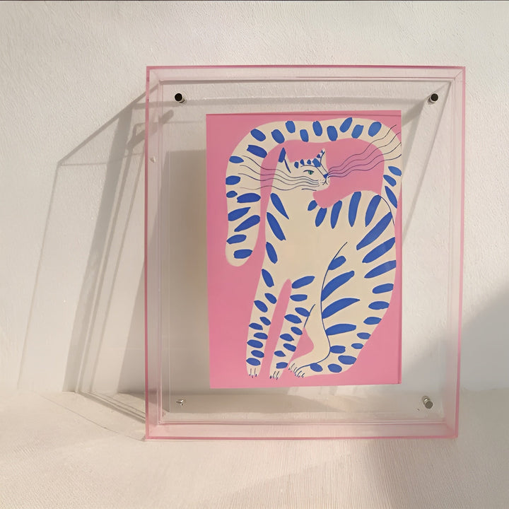Transparenter Rahmen mit zartem rosa Rand, darin ein rosa Druck mit gestreifter Katze in Blau und Weiß. 9