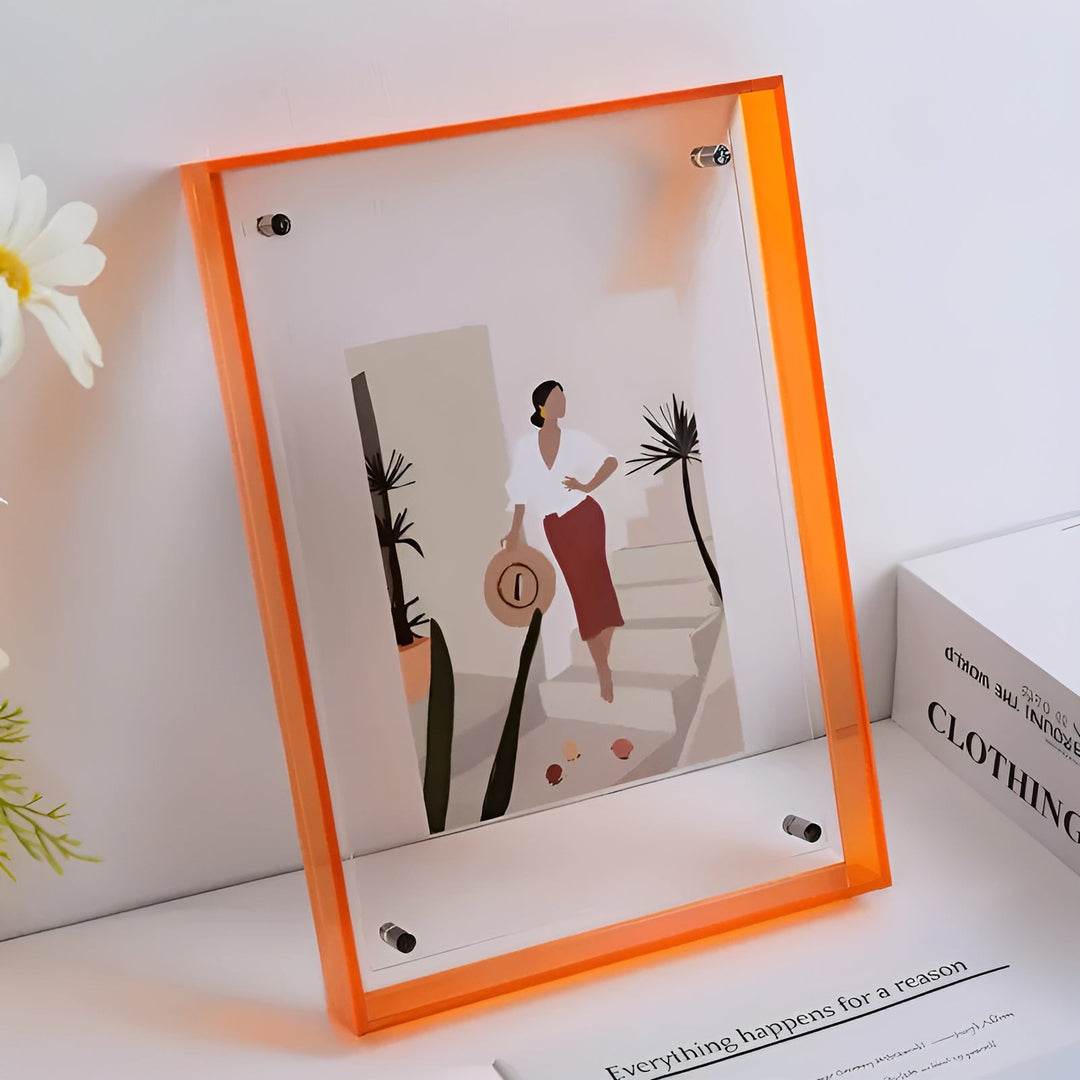 Orangefarbener Acrylrahmen mit sichtbaren Schrauben, darin eine Illustration einer Frau mit Strohhut, daneben Blumen und ein Buch. 10