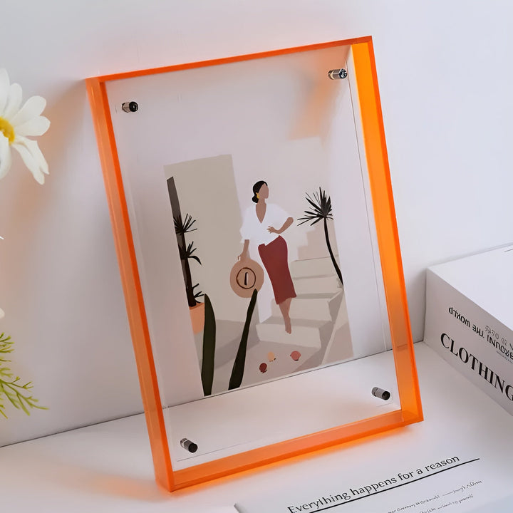 Orangefarbener Acrylrahmen mit sichtbaren Schrauben, darin eine Illustration einer Frau mit Strohhut, daneben Blumen und ein Buch. 10