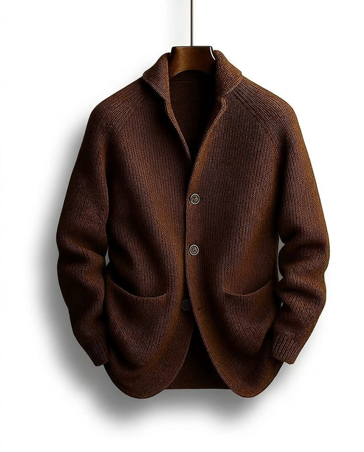 Braune gerippte Strickjacke mit Schalkragen, drei Knöpfen und aufgesetzten Taschen, auf einem Holzbügel hängend, Vorderansicht. 1