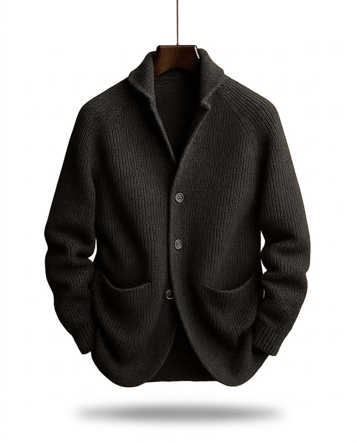 Dunkle, fast schwarze Strickjacke mit Rippstruktur, Schalkragen und Knopfleiste, frei hängend am Bügel mit Schatten darunter. 2
