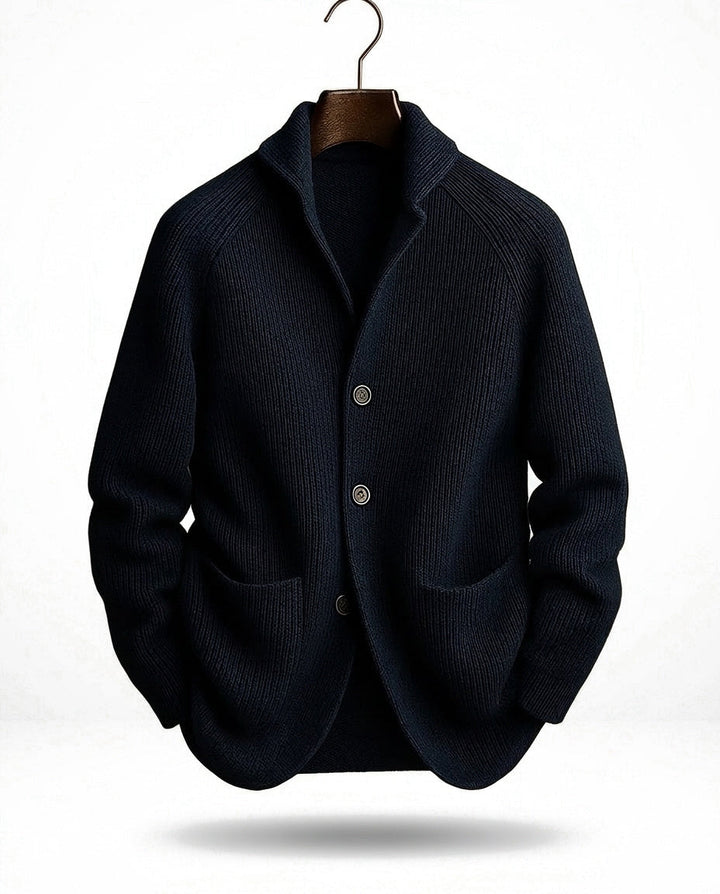 Marineblaue gerippte Strickjacke mit Schalkragen, drei Knöpfen und zwei Taschen, am Haken-Bügel vor hellem Hintergrund. 3