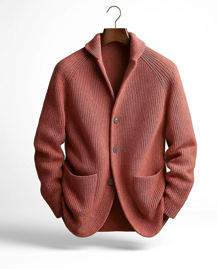 Terrakottafarbene Strickjacke mit Rippmuster, Schalkragen und Knopfleiste, vorne an einem Bügel mit Haken präsentiert. 6