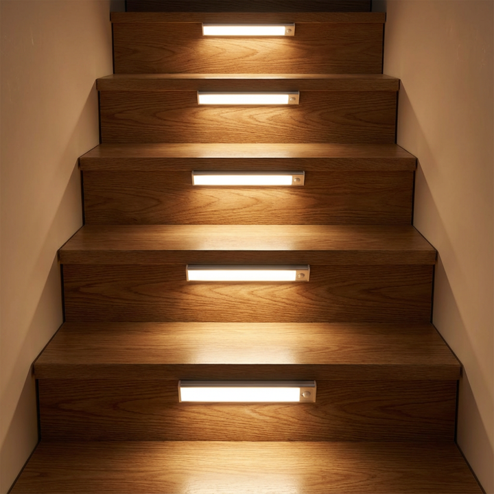 Mehrere Leuchten sitzen mittig an den Stufen einer Holztreppe und beleuchten die Trittflächen in warmem Licht. 2