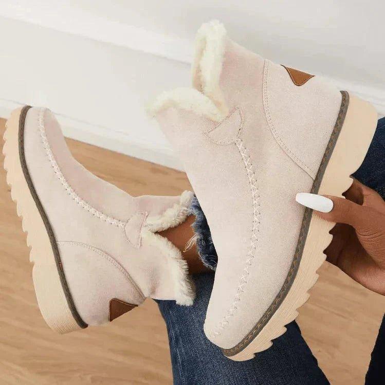 Beige Stiefeletten schräg von oben, eine Hand hält einen Schuh fest und zeigt Plüschfutter, Ziernaht und profilierte Sohle. 6