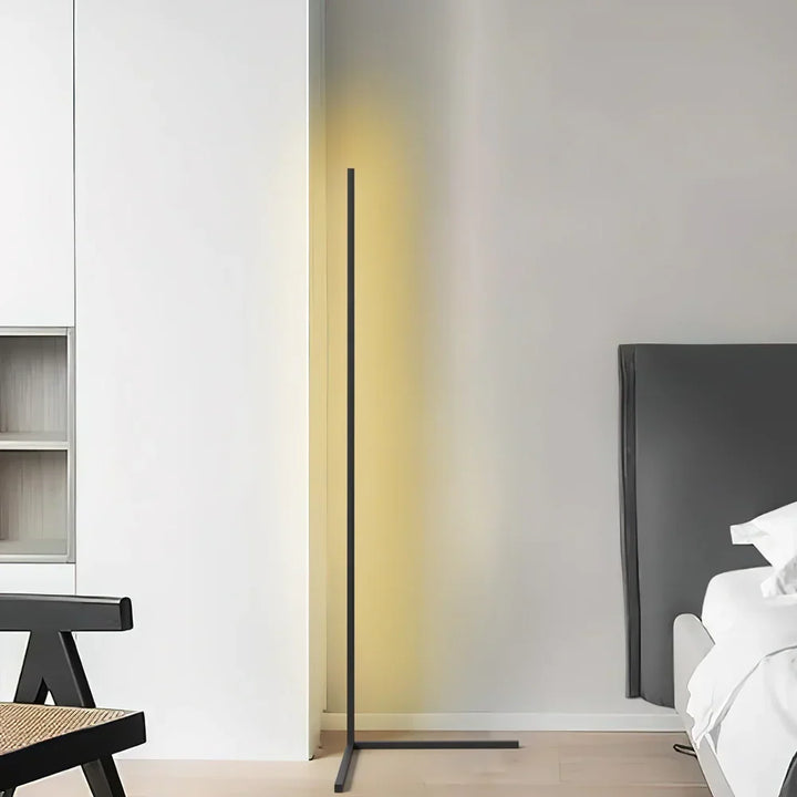 Frontansicht der schwarzen Stehlampe mit gelblichem Schimmer in einem hellen Raum mit Stuhl und Bettkopfteil 7