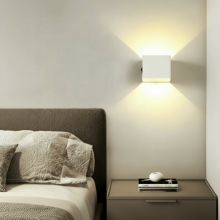 Weiße Würfel-Wandleuchte über einem Nachttisch neben dem Bett, das warme Licht strahlt nach oben und unten. 3