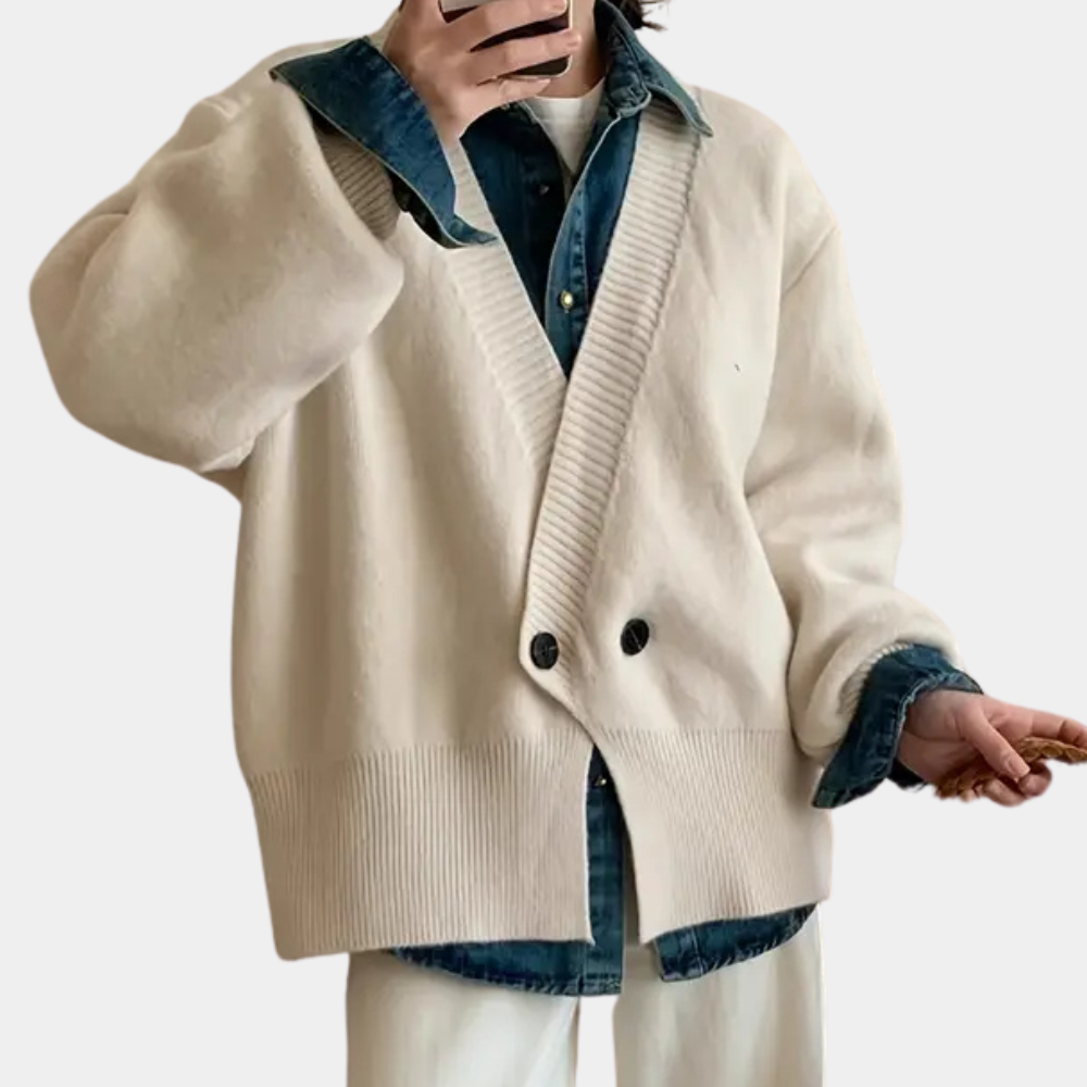 Mann in cremefarbener Strickjacke mit Knöpfen, darunter Jeanshemd, modischer Freizeitlook.