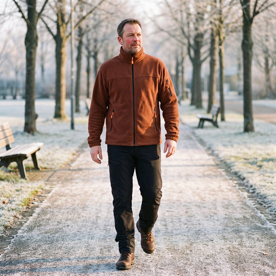 Mann in brauner Fleecejacke und dunkler Hose beim Spaziergang auf einem frostigen Parkweg 2