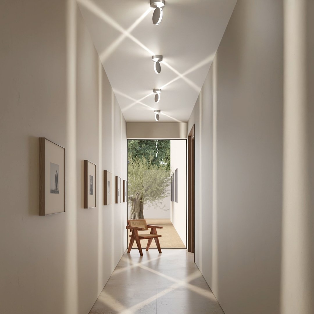 Flur, in dem sich die gekippten Lichtstrahlen der Leuchten an der Decke und am Boden zu Kreuzmustern überschneiden. 7