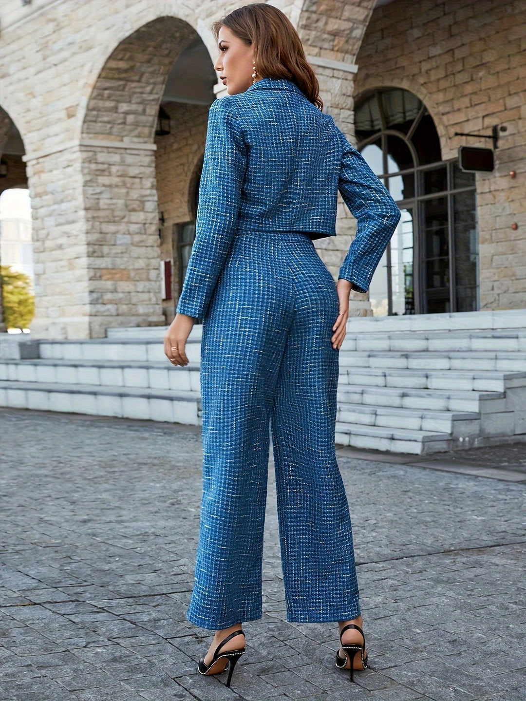 Frau in blauem kariertem Hosenanzug, elegantes Design, modische Damenbekleidung, draußen.