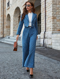 Frau in blauem Hosenanzug, weiße Bluse, braune Tasche, Sonnenbrille, eleganter Look, Straße.