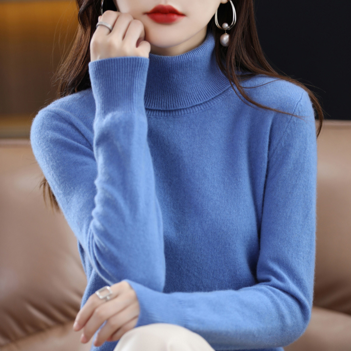 Frau in blauem Rollkragenpullover stützt das Kinn auf die Hand, Nahaufnahme von Kragen und gerippten Bündchen. 3