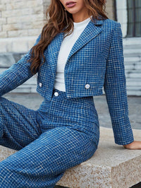Frau in blauem Tweed-Anzug und weißem T-Shirt, sitzt auf Steinbank, modisch, elegant.