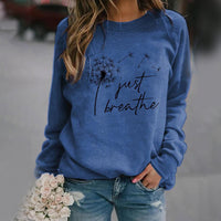 Frau in blauem Sweatshirt mit "Just Breathe"-Aufdruck, hält weiße Rosen, lässiger Stil.
