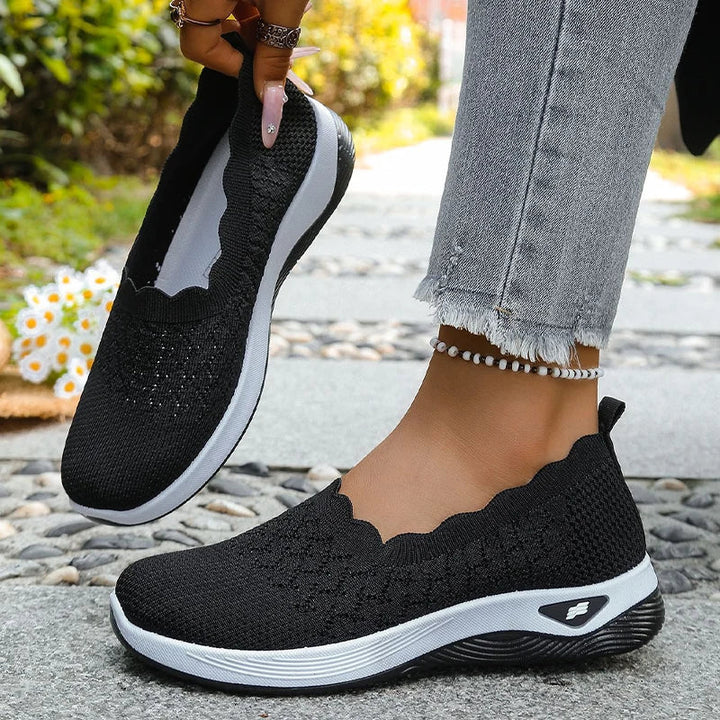 Schwarze Strick-Slip-ons, ein Schuh am Fuß, der andere angehoben, Innenfutter sichtbar 13