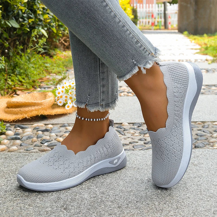 Graue Slip-ons mit weißer Sohle an den Füßen, Spaziergang auf einem Steinweg 12