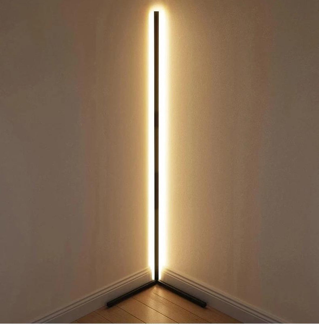 Schwarze Stehlampe steht in einer Raumecke und strahlt warmweißes Licht an beide Wände 12