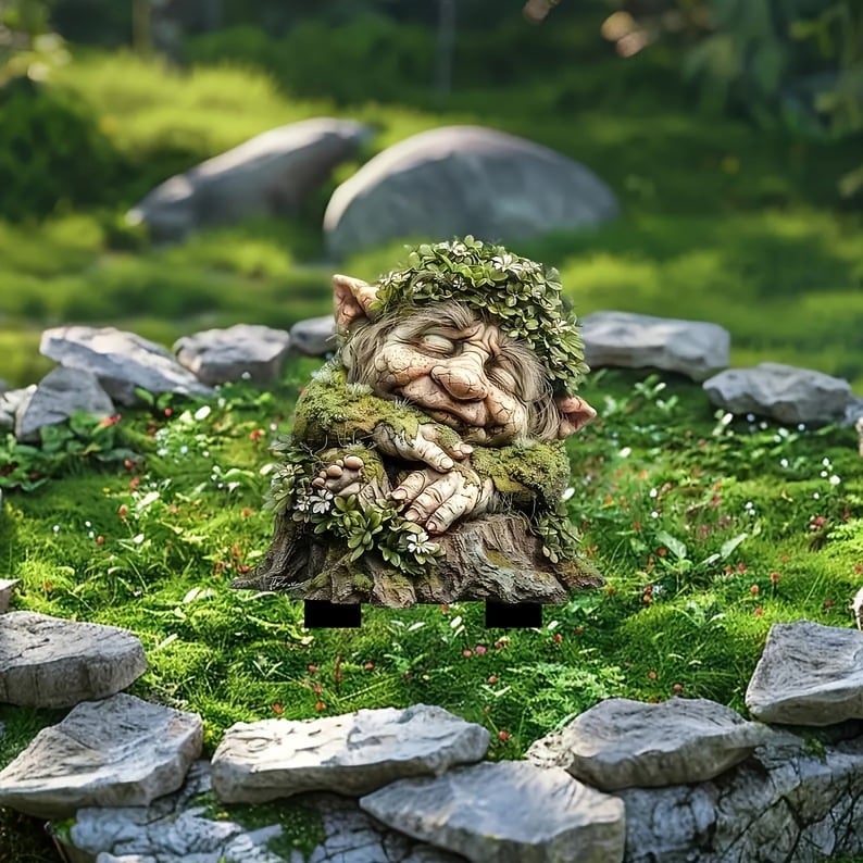 Schlafender Troll mit Blätterkranz auf Baumstumpf, mit schwarzen Steckfüßen auf einer Moosfläche mit Steinen aufgestellt. 18