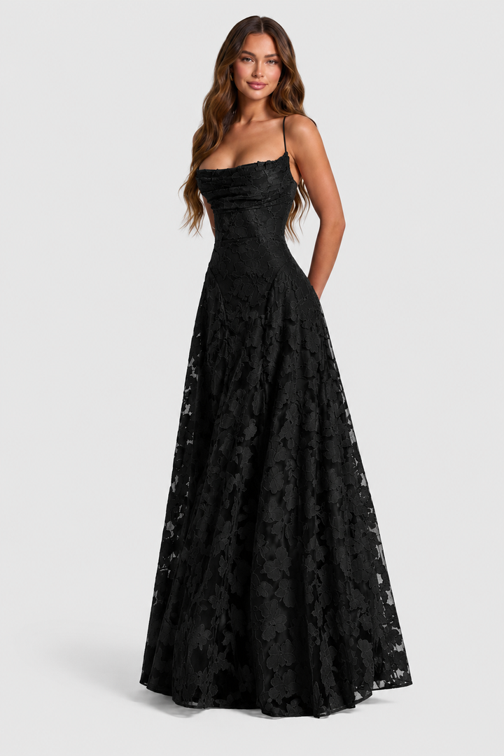 Schwarzes Spitzenkleid mit drapiertem Ausschnitt und schmalen Trägern, frontal am lächelnden Model, Hände hinter dem Rücken. 10